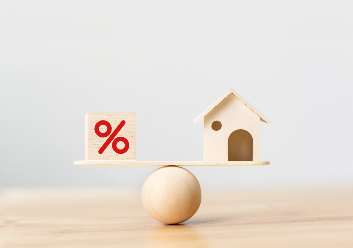  Projet immobilier à Montpellier – Cube pourcentage et maison en équilibre sur une planche posée sur une boule en bois.