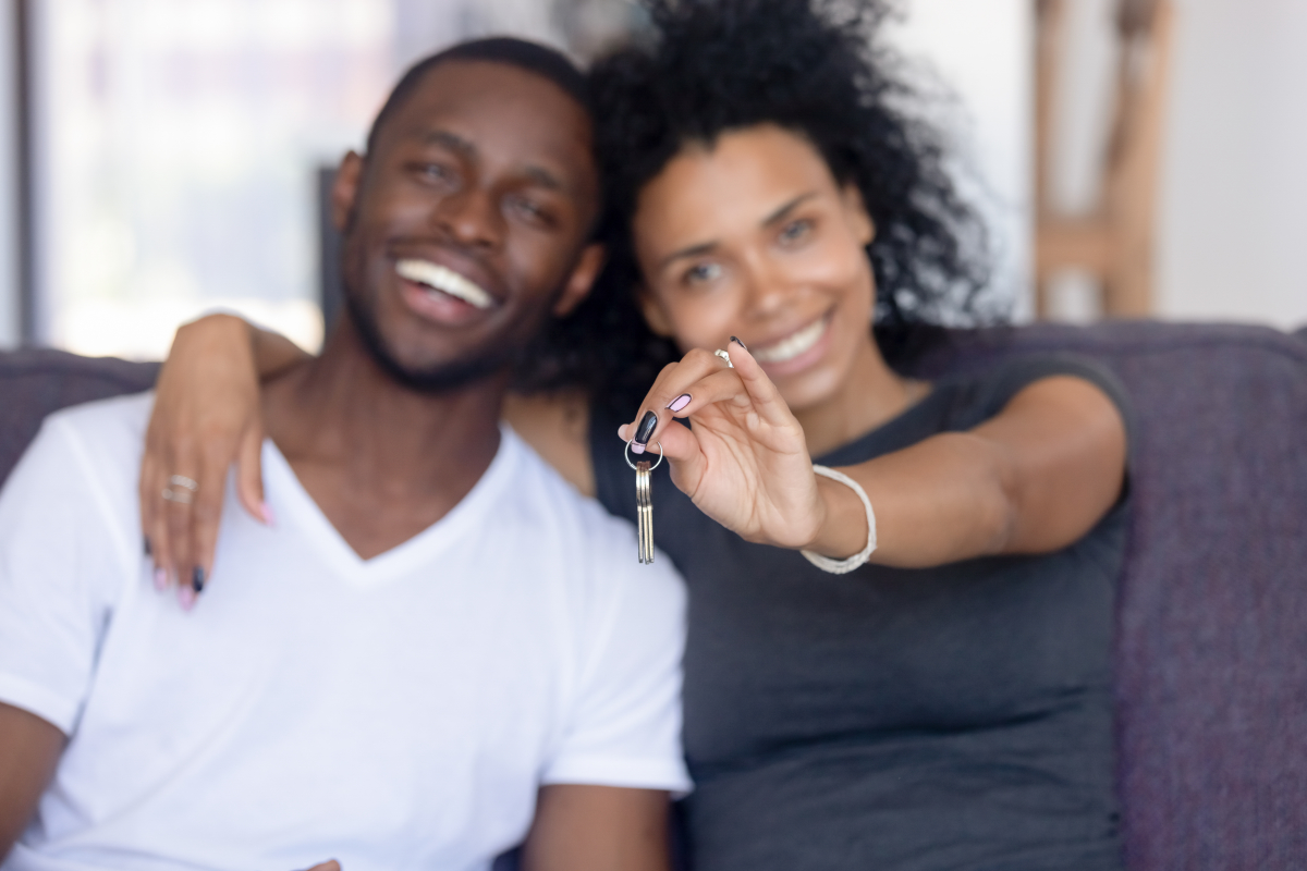 ”un couple afro-américain montre les clefs d'une maison qu'ils viennent d'acheter”