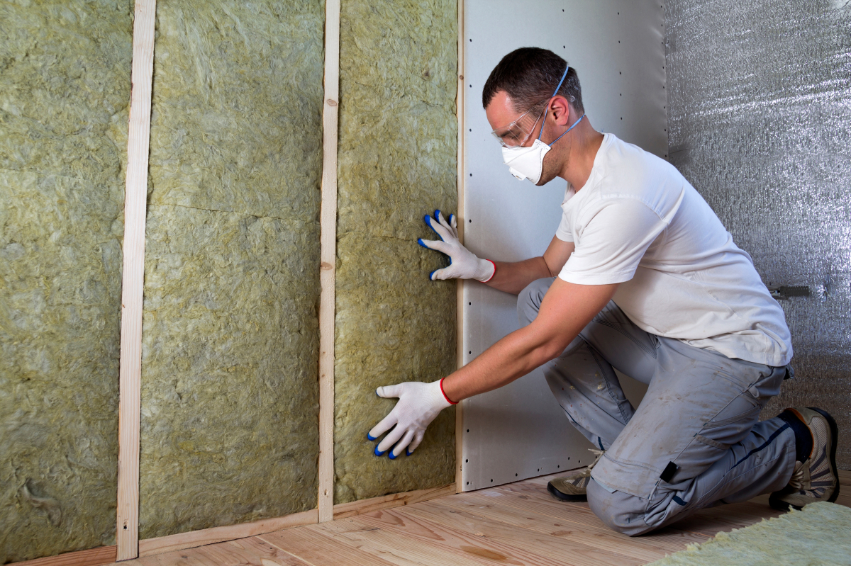 interdiction location dpe g – Un homme posant une isolation sur un mur
