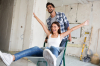 immobilier neuf à Montpellier - couple heureux en plein chantier dans leur logement neuf, la femme lève les bras en souriant