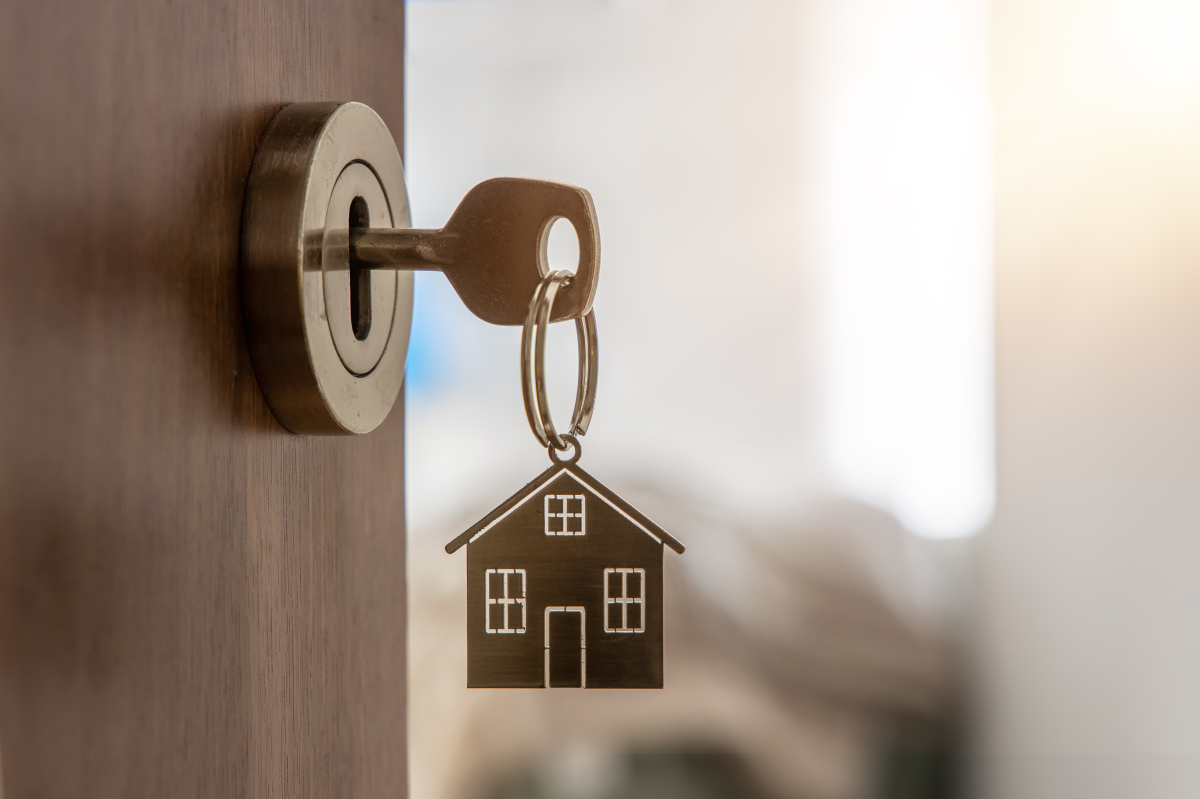 Louer un appartement à Montpellier - Clés avec un porte clé en frome de maison sur une porte ouverte