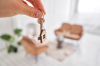 Nouveau zonage loi Pinel 2022 – Une main tient un porte-clé avec la clé d’un appartement et une petite maison en bois