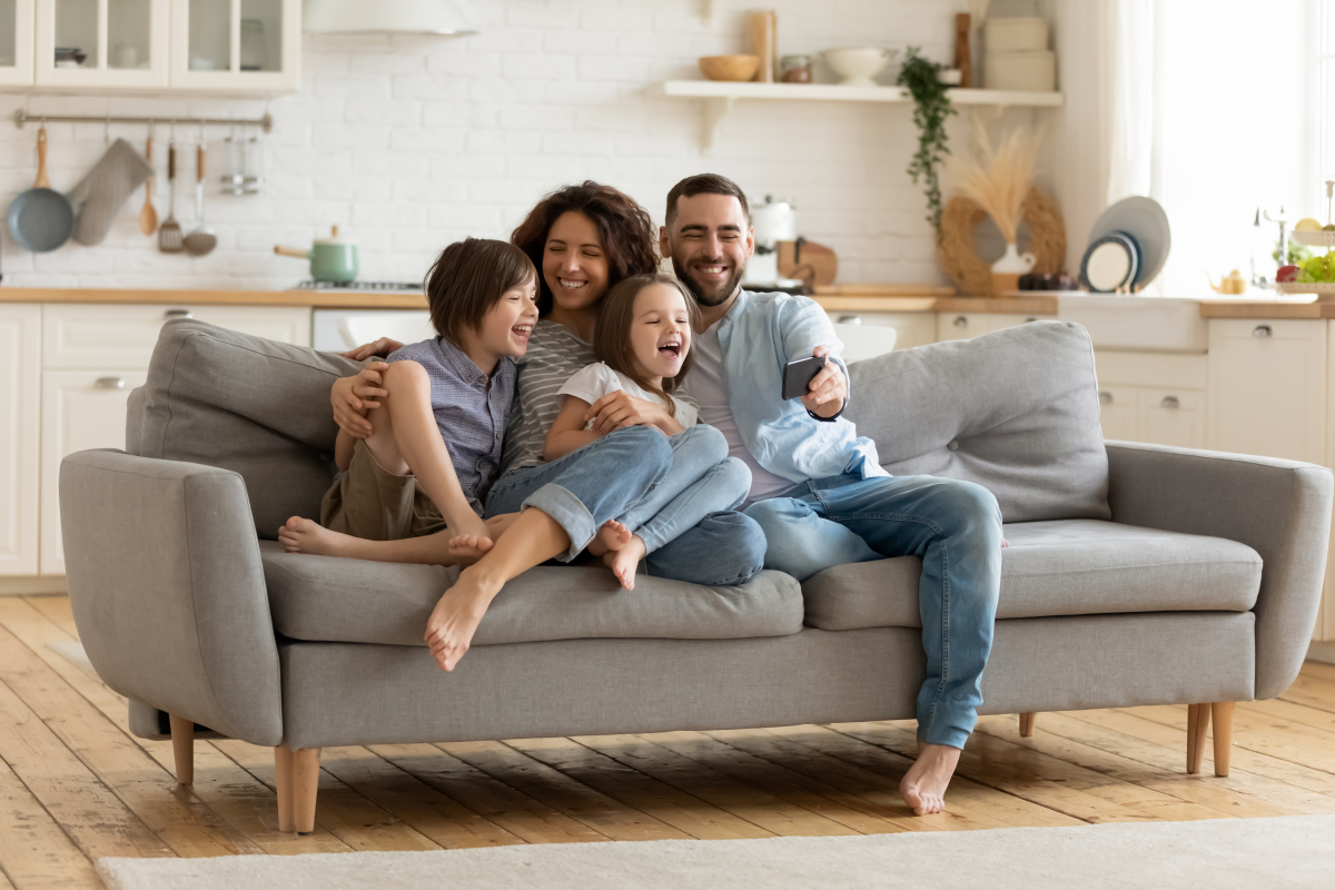 L’investisseur en LMNP peut déclarer l’amortissement sur les biens meubles du logements LMNP à Montpellier – De jeunes parents avec leurs enfants riant sur le canapé de leur appartement