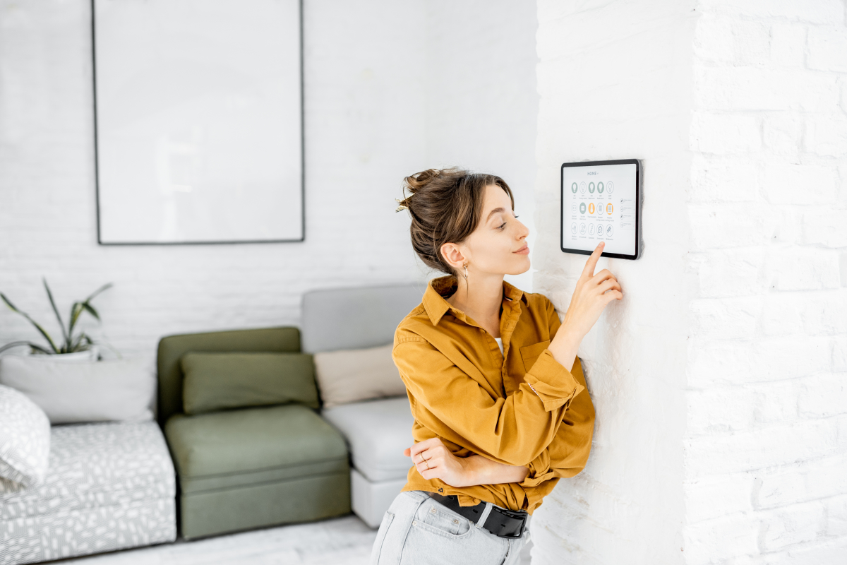 Immobilier écologique - Jeune femme contrôlant la température de son appartement via son smartphone