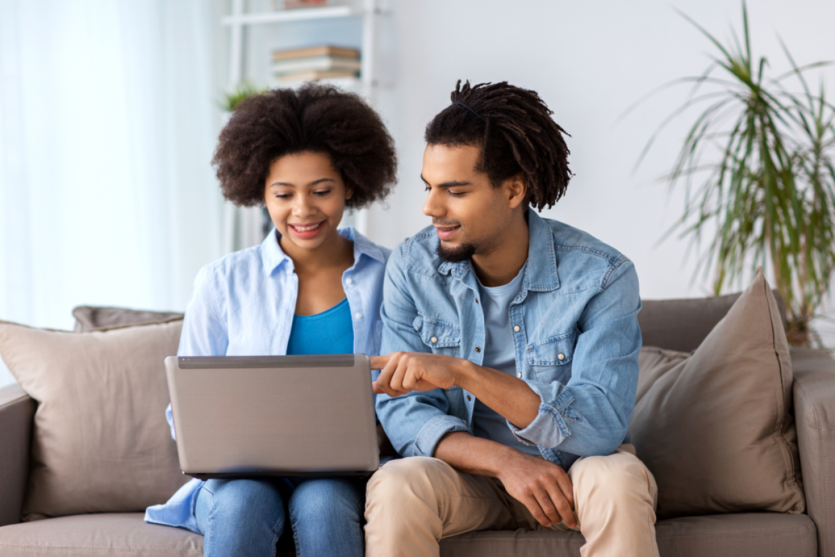 Investir dans l’immobilier en loi Pinel ou LMNP à Montpellier Investissement locatif Montpellier avec un petit budget – Couple assis sur un canapé regarde des annonces immobilières sur leur ordinateur portable