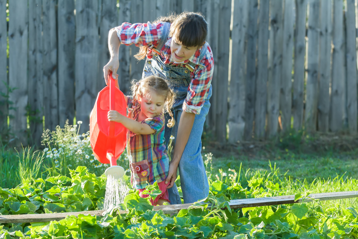 espaces verts à Montpellier – une petite fille arrose le jardin avec sa maman