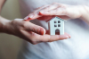 loi assurance emprunteur – Une femme tenant dans ses main une maison miniature