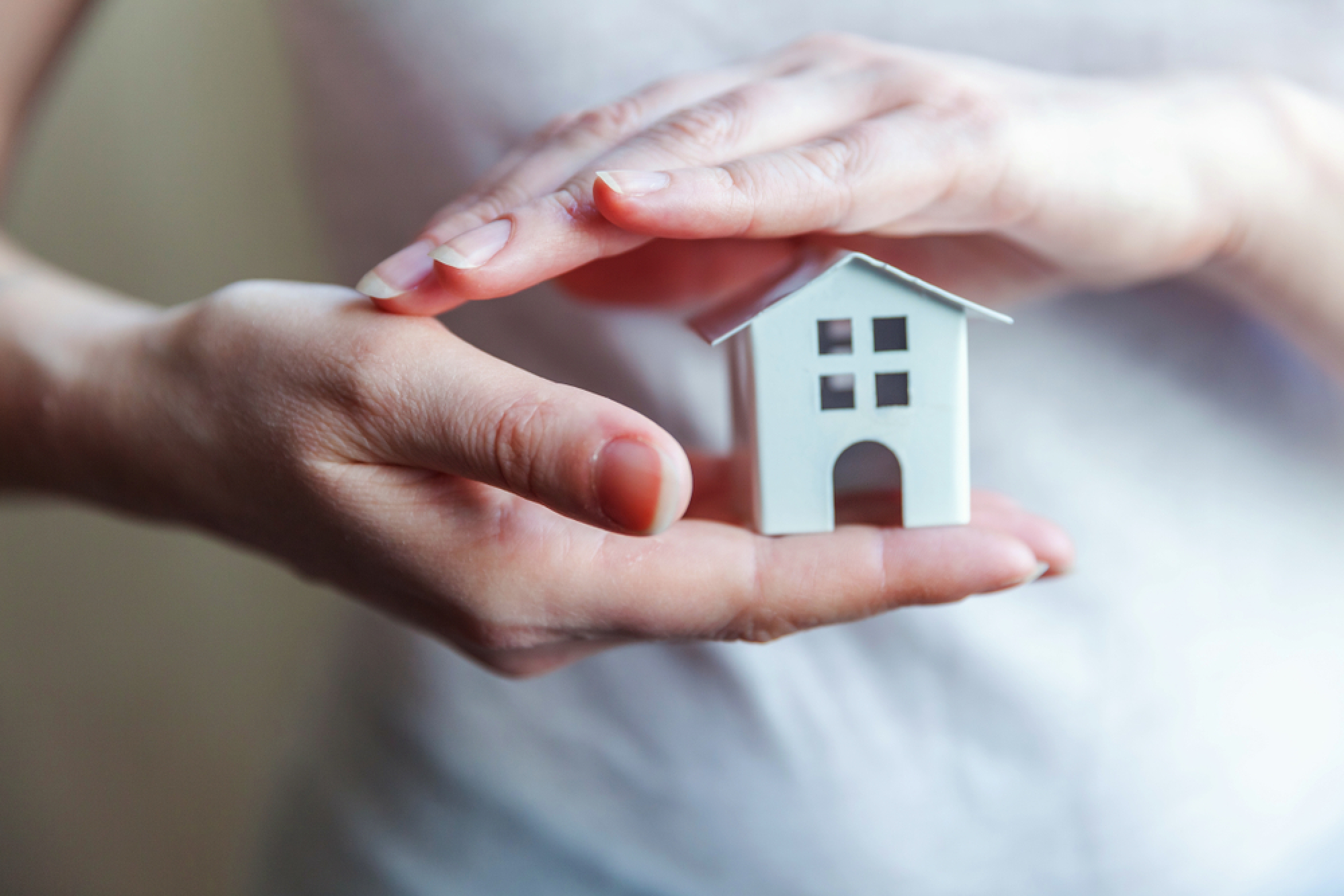 Femme tenant une maison miniature entre ses mains