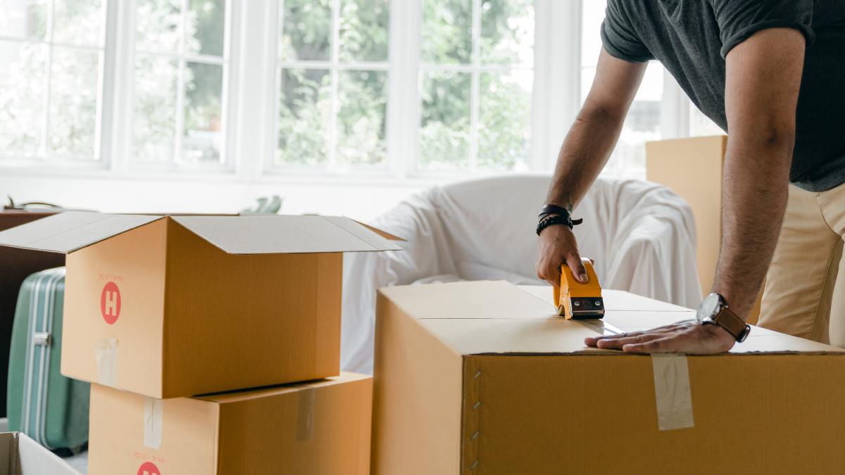 plafond Pinel Montpellier – Une homme en train de fermer des cartons de déménagement