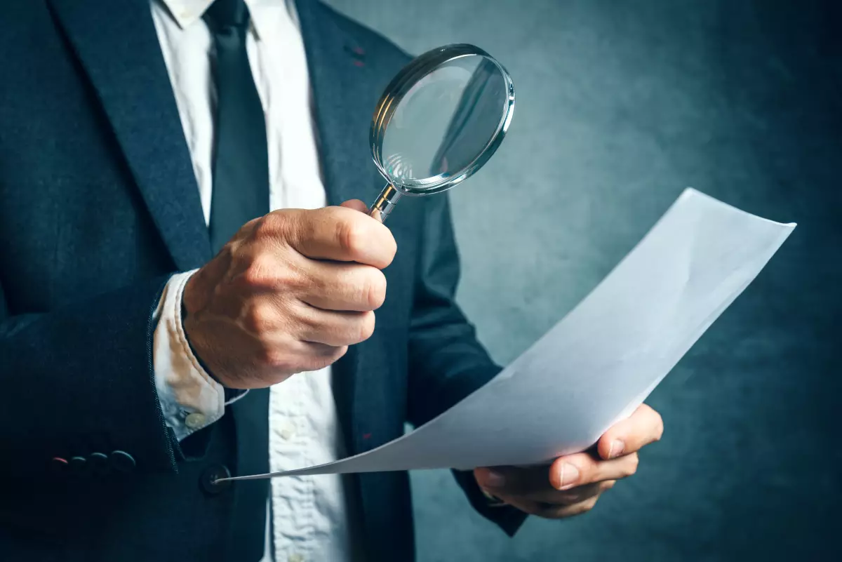 exonération de donations achat logement neuf - homme regardant une feuille de papier à la loupe