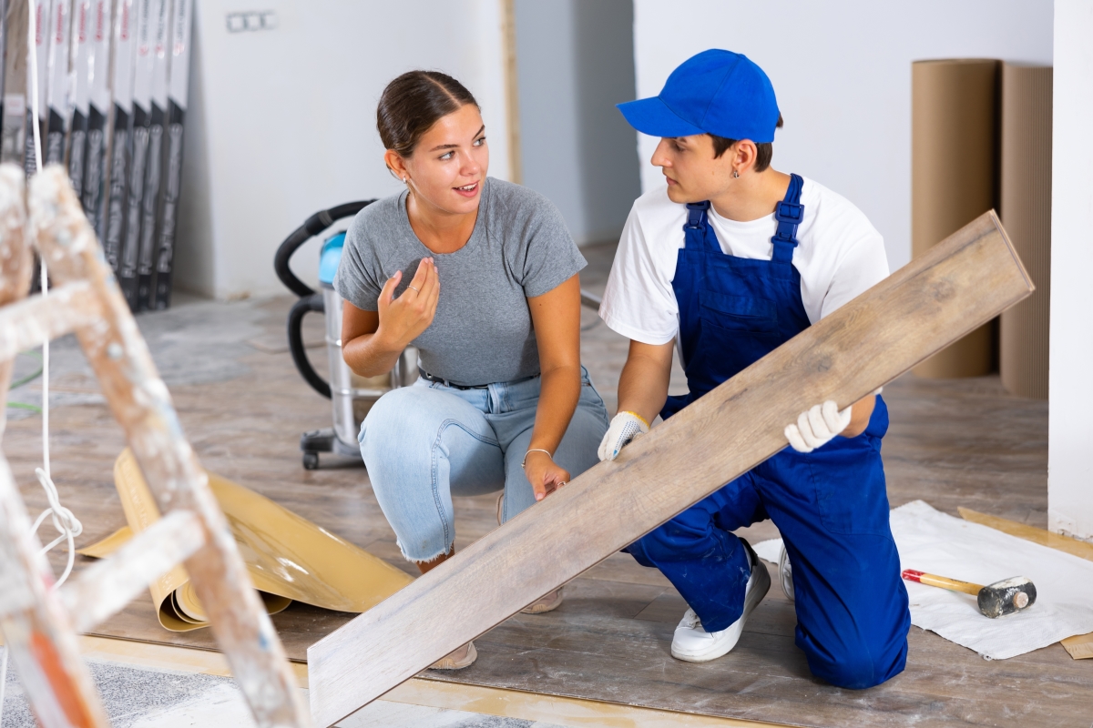 Il ne faut pas confondre travaux réservés et TMA travaux modificatifs acquéreur – une femme parle à un ouvrier qui pose du parquet
