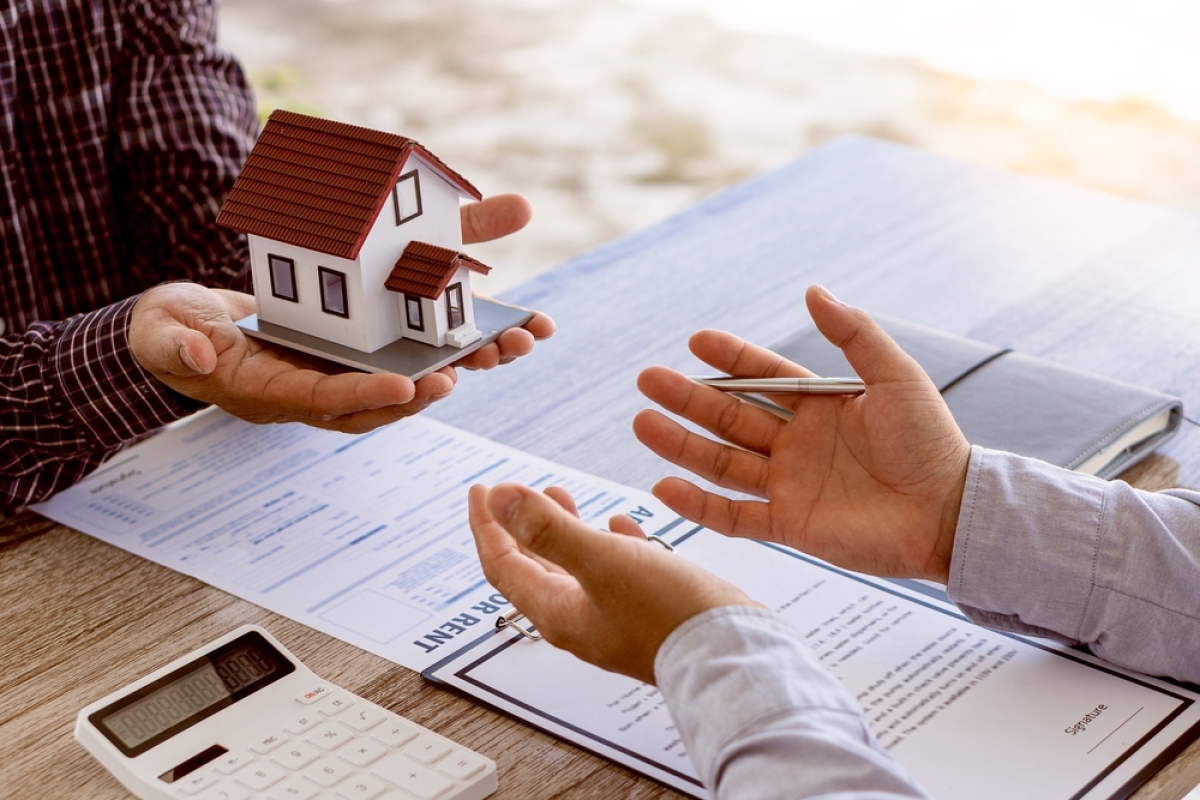 Il est important de choisir un programme neuf réalisé par un promoteur immobilier de confiance comment trouver un programme neuf – une personne tend une maquette de maison à une autre qui va signer un contrat