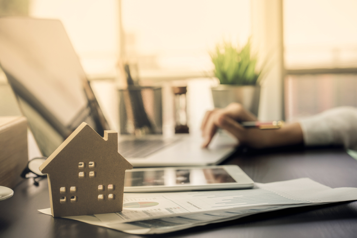 Le mois de décembre 2023 marque la dernière hausse du taux d’usure de l’année taux d'usure 2023 – une maison posée sur un bureau avec une personne sur un ordinateur en arrière-plan