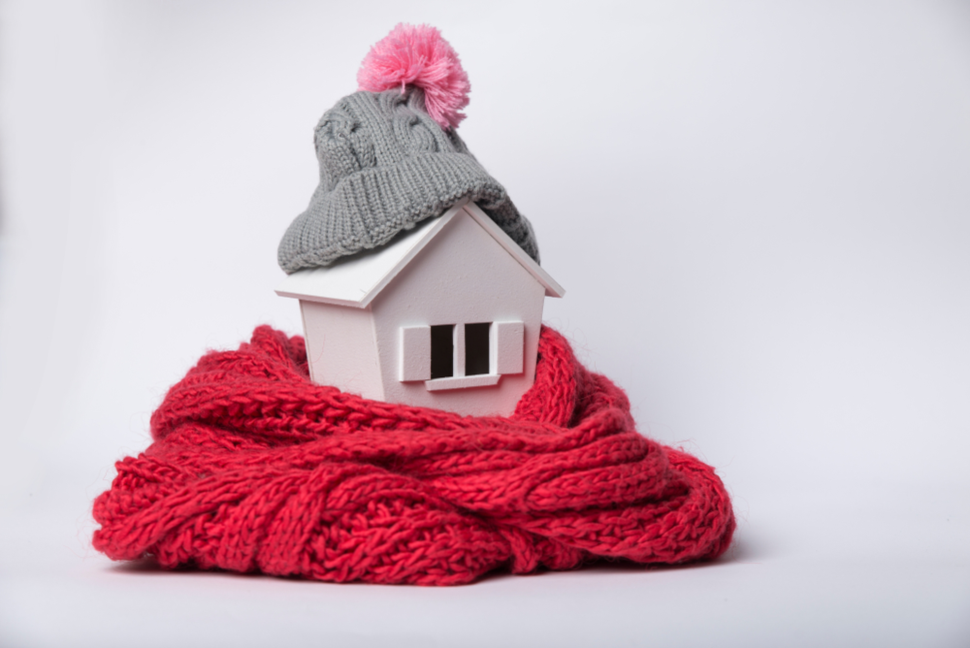 Une petite maison blanche habillée d'un bonnet et d'une écharpe de laine