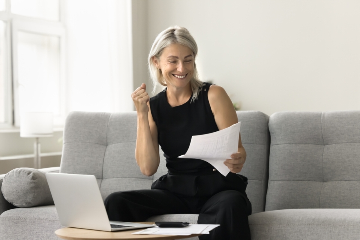 taxe logements vacants – Une femme âgée tient des documents importants en souriant