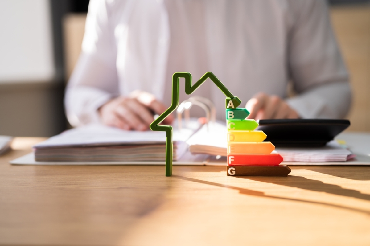 Les performances énergétiques d’un logement neuf sont un argument incontournable pour une décision d’achat achat neuf ou ancien 2024 – Une représentation des étiquettes du DPE avec un homme consultant un classeur en fond