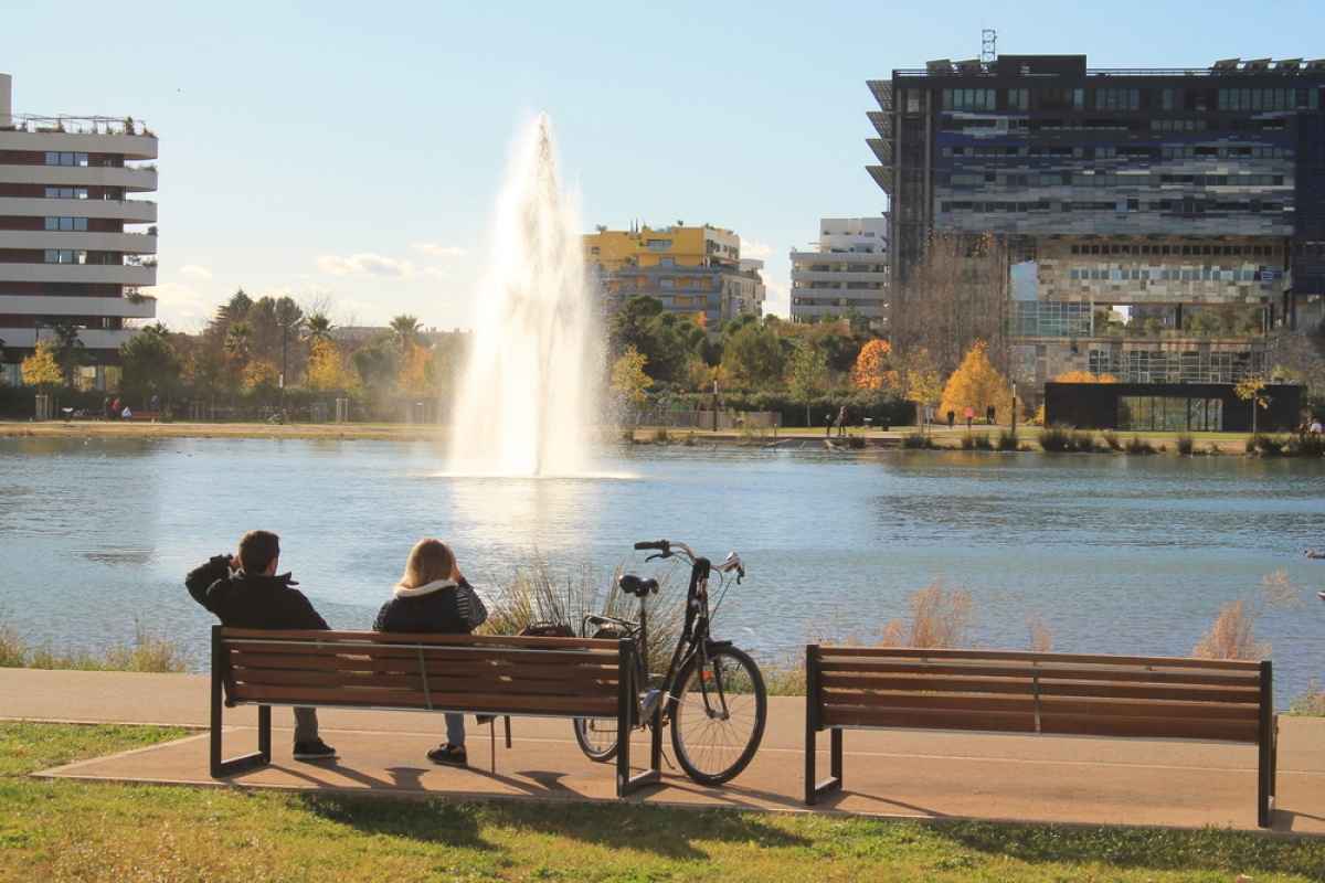 Port-Marianne est le quartier le plus en vue de Montpellier où investir à Montpellier en 2024 – deux personnes sur un banc devant le bassin Jacques Cœur à Port-Marianne