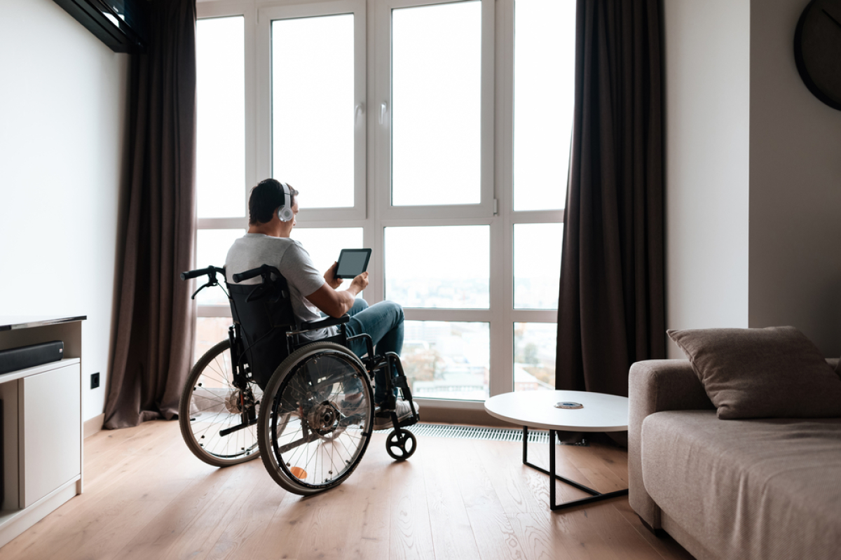 normes PMR immobilier neuf – une personne à mobilité réduite écoute la musique dans son appartement devant sa fenêtre