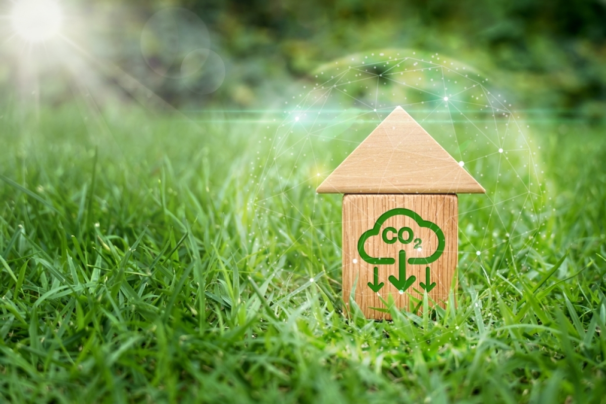 rénovation école grabels – une petite maison en bois dans l’herbe avec un symbole CO2 direction la terre
