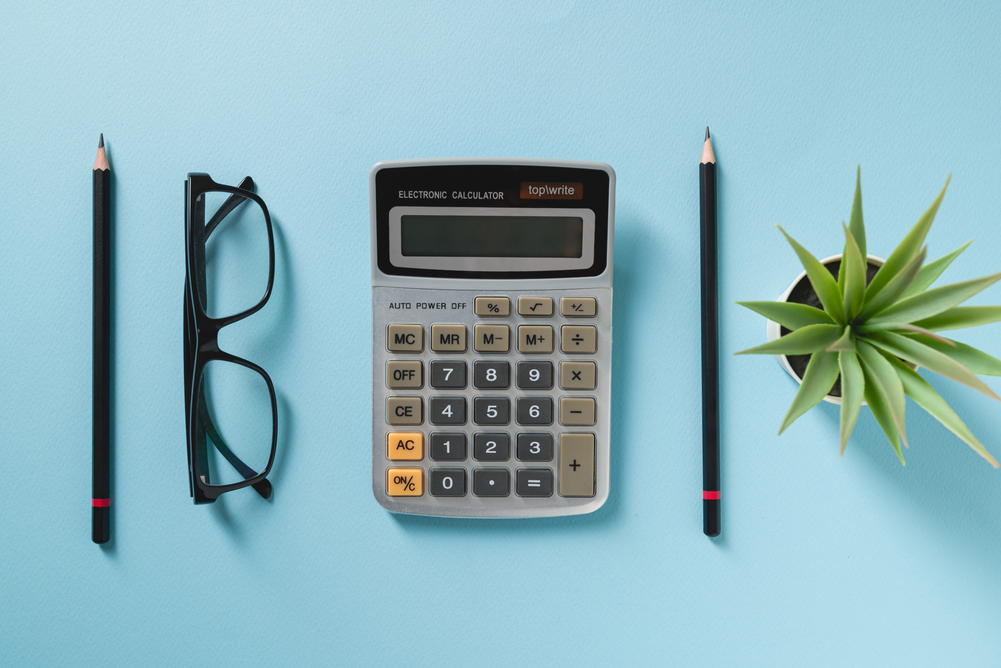calculette lunettes plante et crayon sur fond bleu