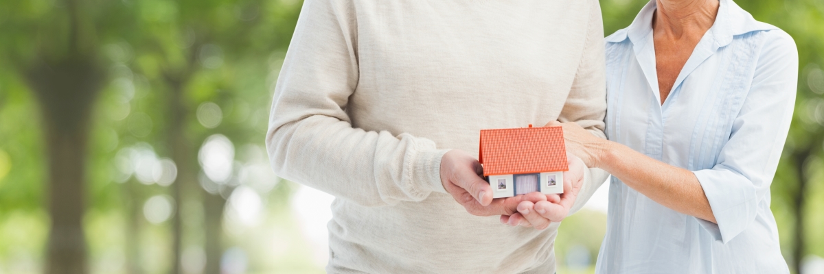 si s’engager dans un prêt immobilier à la retraite est possible, les conditions d’emprunts, elles, différent nettement. des personnes âgées tiennent une maquette de maison dans leurs mains