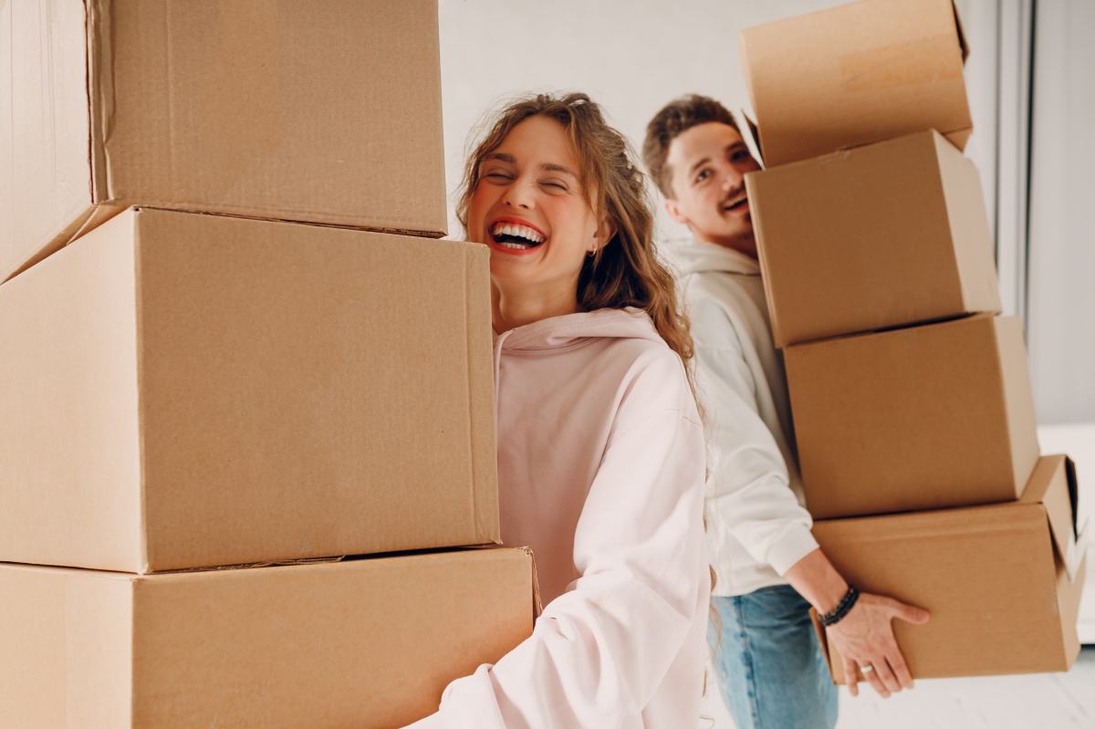 des aides à l’achat immobilier existent pour les primo-accédants en France. un couple de jeunes porte des piles de cartons en riant