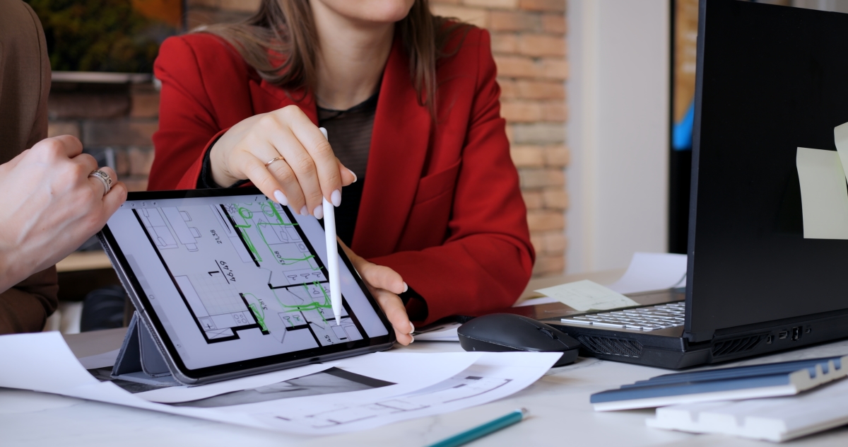 La demande de TMA se fait via le promoteur travaux modificatifs acquéreur – Une femme montre un plan de logement sur une tablette