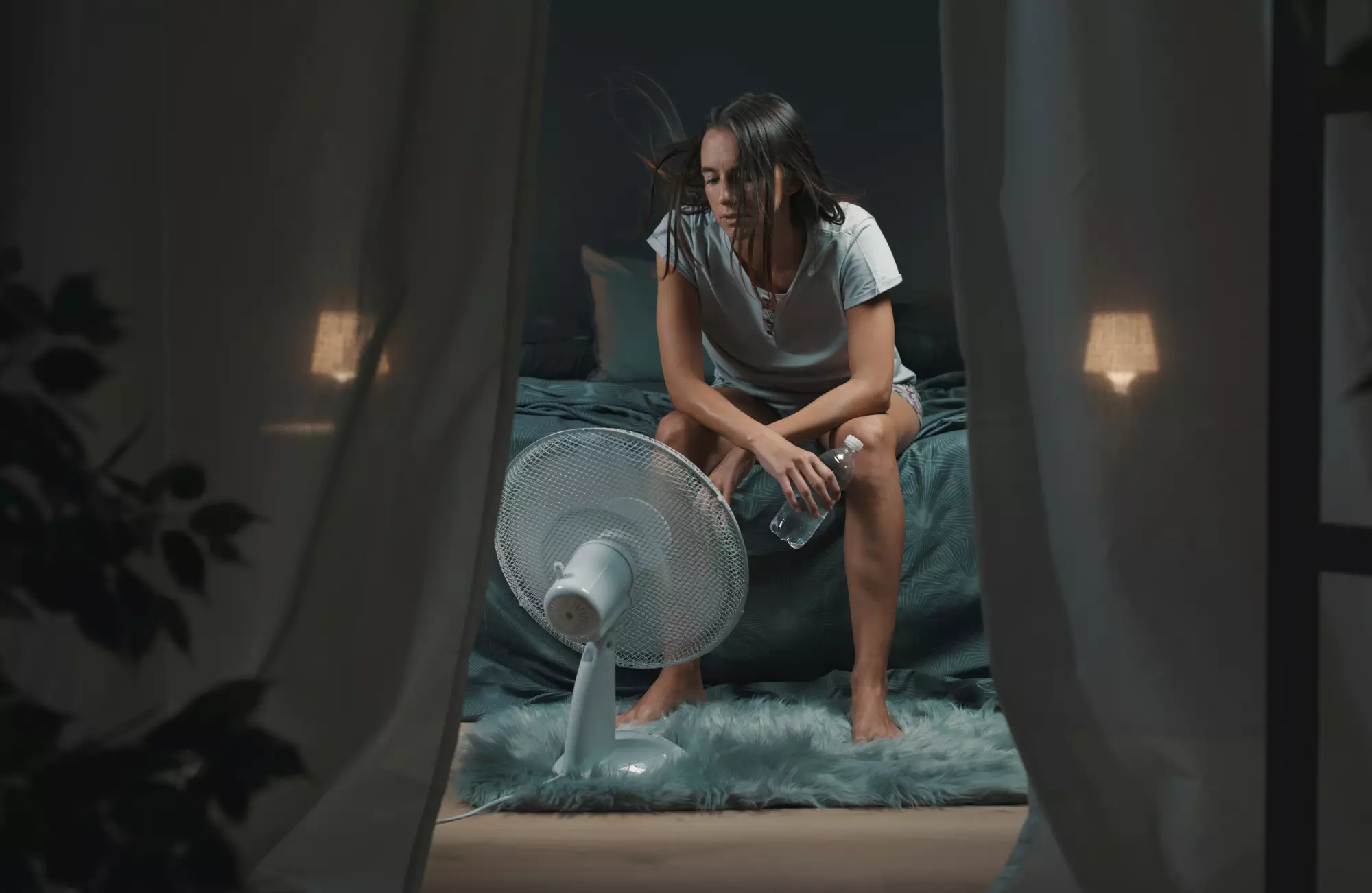 Une femme qui n’arrive pas à dormir à cause de la chaleur s’assoit à côté de son ventilateur